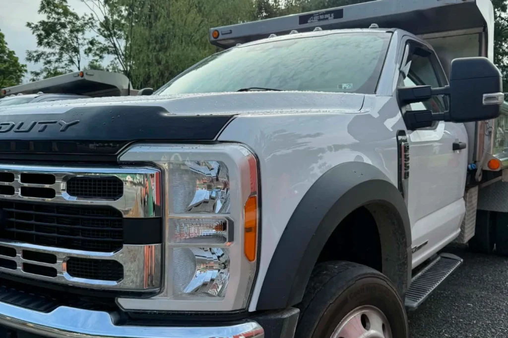 White pickup truck front close-up with grille and headlights in an outdoor parking lot